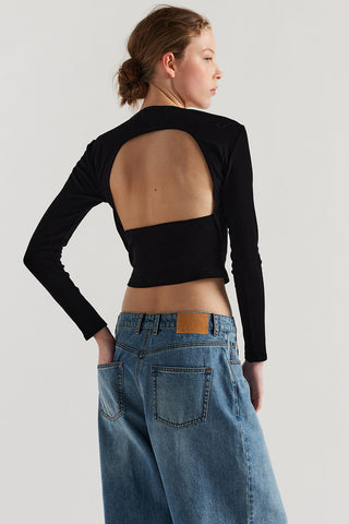 Back view of woman wearing black long sleeve open back top and baggy jeans. 