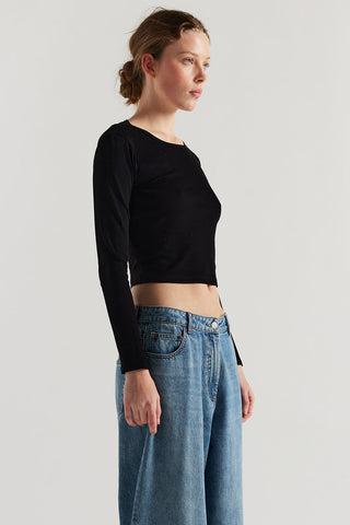 Woman wearing black long sleeve slightly cropped shirt and baggy jeans. 