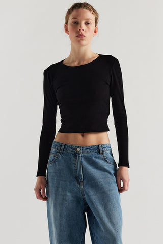 Woman wearing black long sleeve slightly cropped shirt and baggy jeans. 