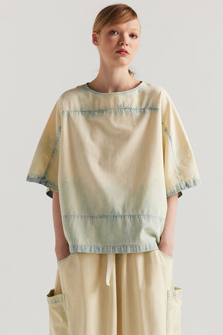 Woman wearing faded denim relaxed fit top with matching drawstring waist skirt. 