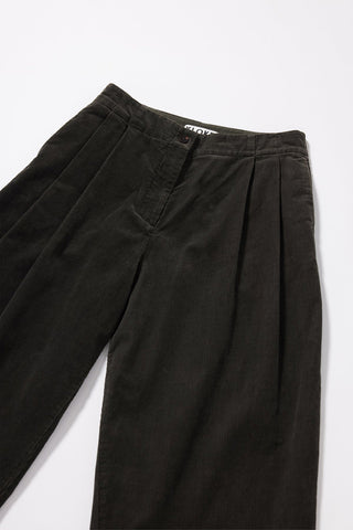 Dark green / brown pleated wide-leg trousers laid flat on a light gray background, showing the waistband, button closure, and front pockets.