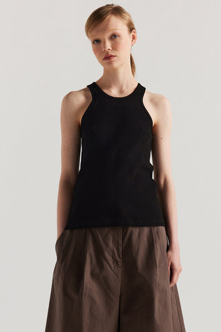 Woman wearing black racerback tank top with wide brown shorts. 