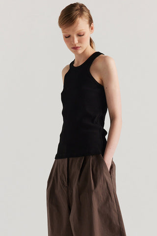 Woman wearing black racerback tank top with wide brown shorts. 