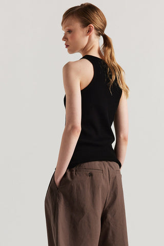 Back view of woman wearing black racerback tank top with wide brown shorts. 