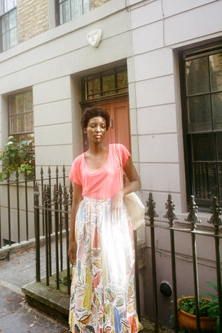 Woman standing on street wearing pink t-shirt and colourful Isaac skirt by LF Markey. 