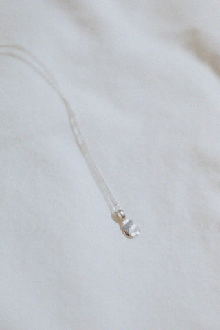Silver pebble pendant necklace on white background. 