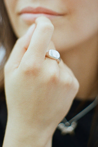 Close-up of woman's hand wearing sterling silver signet ring. 