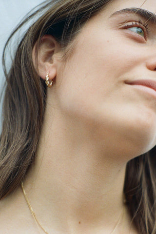 Close-up of woman wearing gold braided sleeper hoop earrings