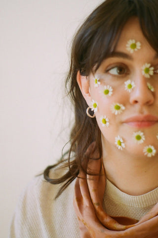 Woman with flowers on face wearing gold vermeil Flot earrings by La Manufacture Fait Main. 