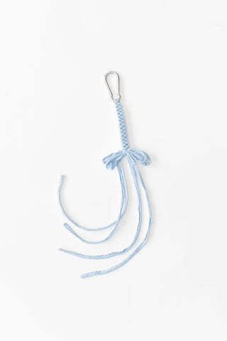 Baby blue crocheted bag charm on white background. 