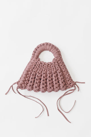 A dusty rose pink chunky crochet handbag with a circular top handle displayed, flat against a clean white background.