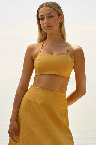 Woman wearing yellow bustier top with matching skirt. 