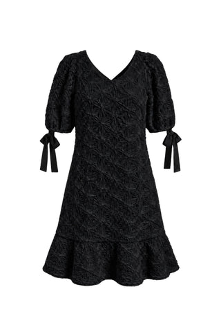 Black embroidered babydoll dress with v-neckline, puff sleeves, bows at cuffs and ruffle hem, shown against white background. 