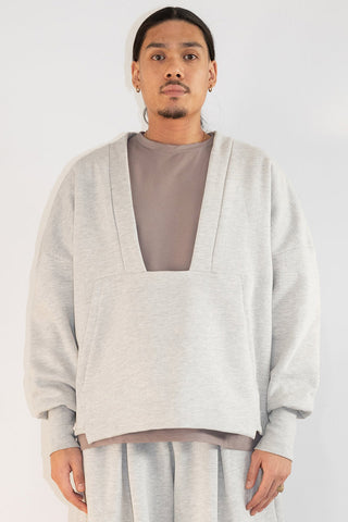 Man in front of white background wearing light grey oversized shawl collar sweater. 