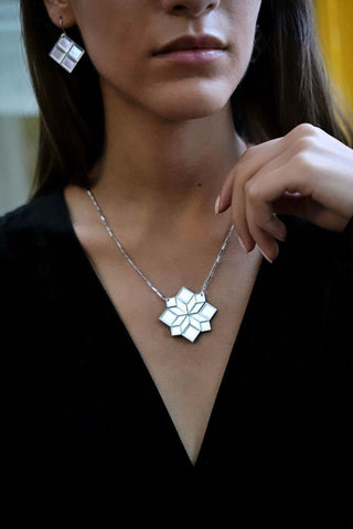 Woman wearing black top and silver mirror geometric 45 Cross Mim Té necklace. 