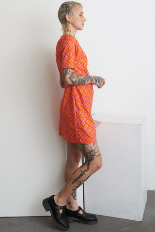 Side view of model wearing orange and pink Sugar Cube print Muto dress by Osei Duro. 