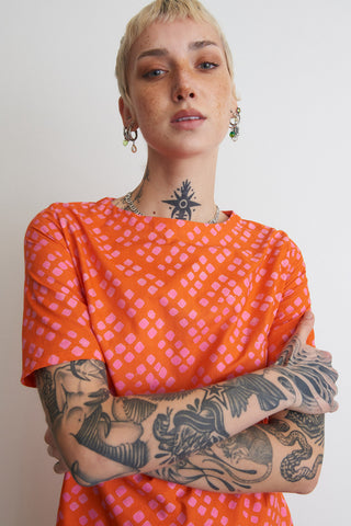 Close-up of model wearing orange and pink Sugar Cube print Muto dress by Osei Duro. 