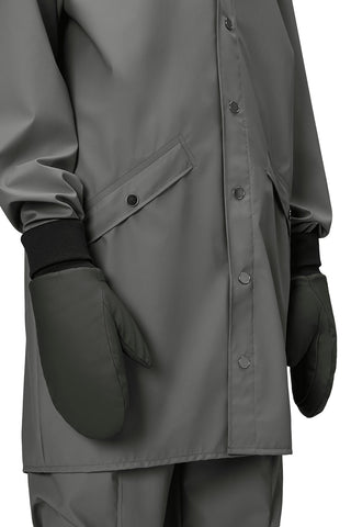 Close-up of person wearing grey jacket and dark green mittens. 