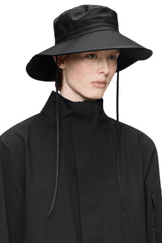 Woman wearing black wide rim hat with ties. 