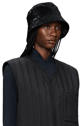 Woman wearing black waterproof bucket hat and black vest. 