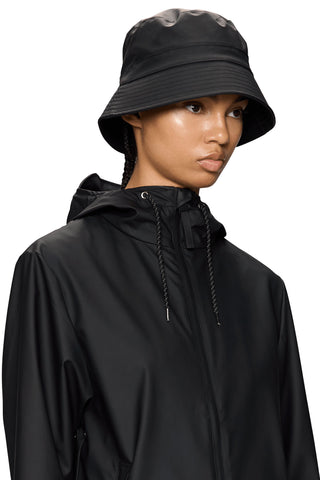Woman wearing black waterproof bucket hat and black rain jacket. 