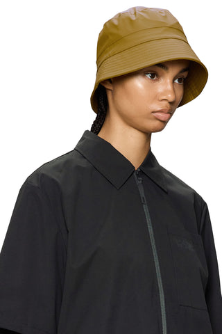 Woman wearing camel waterproof bucket hat and black rain jacket. 