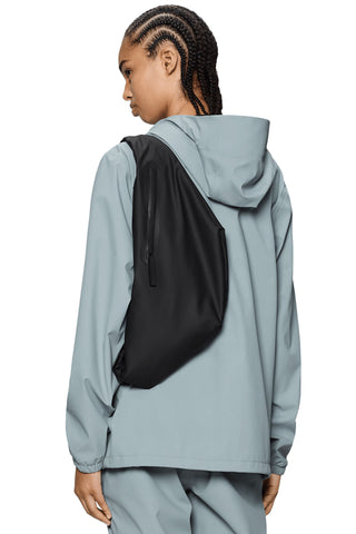 Person wearing light blue jacket and black waterproof oversized Bum Bag. 