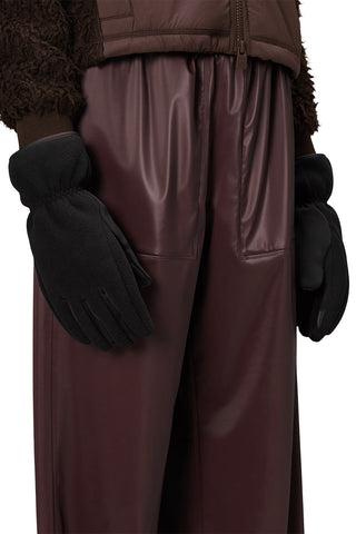 Close-up of person wearing burgundy sweater and pants with black heavy fleece gloves. 