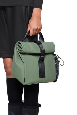 Person holding green roll top large size lunchbag with black strap closure and water bottle holder. 