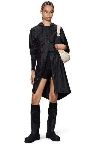 Woman wearing black knee length rain coat with drawstring waist and hood. 