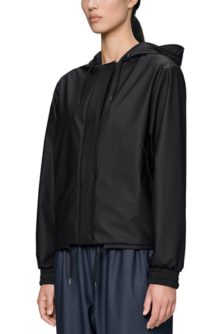 A woman wearing a black hooded zip-up jacket with elasticized cuffs, paired with navy drawstring pants, against a plain white background.