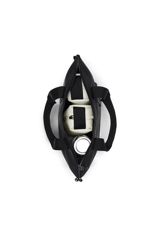 A top-down view of a black tote bag open with bottle and two packing cubes inside. 