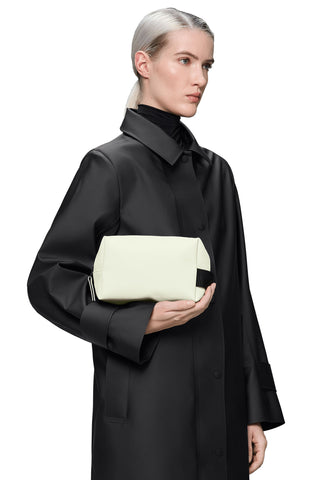 Woman holding ivory waterproof toiletry bag. 