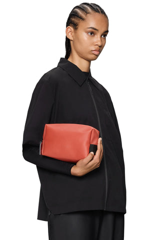 Woman holding red-orange waterproof toiletry bag. 