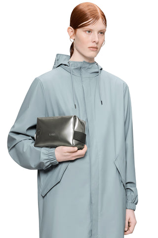 Woman holding silver waterproof toiletry bag. 