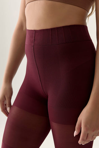 Close-up of burgundy contour-shaping waistband on tights. 