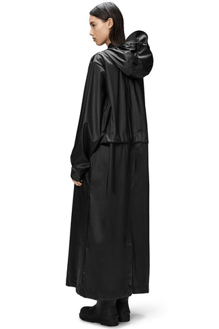 Back view of model wearing black unisex waterproof and windproof full length Bold Longest Jacket by RAINS. 