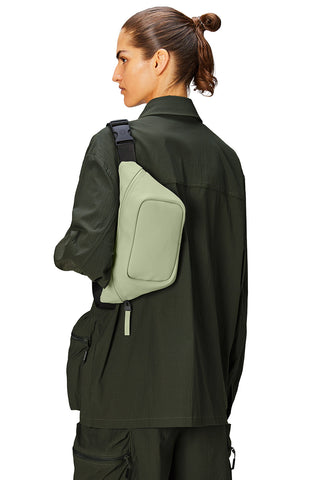 Model wearing light green waterproof Bum Bag Mini W3 by Rains. 