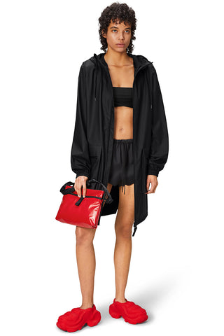 Woman wearing black waterproof Cargo Long Jacket by RAINS. 