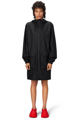 Woman wearing black waterproof Cargo Long Jacket by RAINS.  