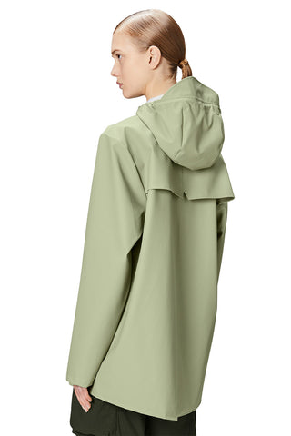 Back view of woman wearing light  green waterproof rain jacket W3 by Rains.