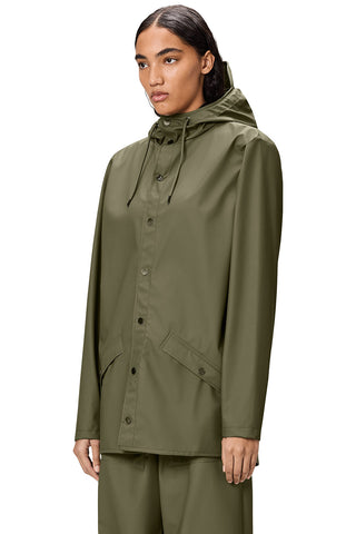 Close-up of woman standing in front of white background wearing Marsh (green) unisex waterproof RAINS jacket. 