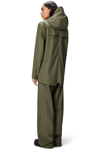 Back view of woman standing in front of white background wearing Marsh (green) unisex waterproof RAINS jacket.
