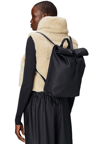 Woman wearing black Roll Top Mini W3 backpack by RAINS. 