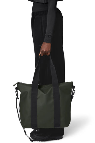 Woman carrying dark green waterproof Rains Tote Bag Mini. 