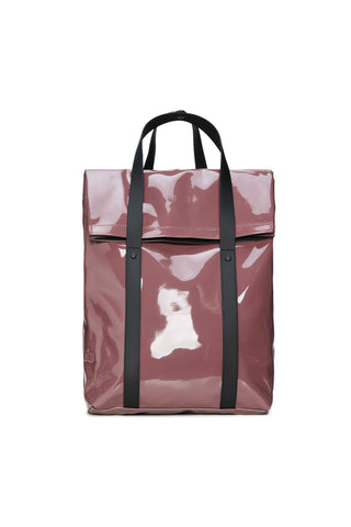 A glossy, dusty rose vinyl tote backpack with black handles and vertical straps, set against a plain white background.