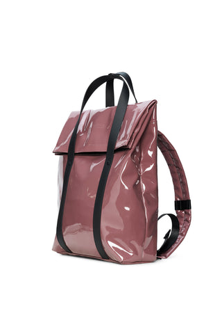 A glossy, dusty rose vinyl tote backpack with black handles and vertical straps, set against a plain white background.