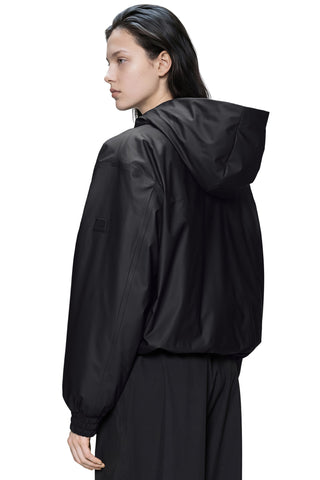 A model shown from the back wearing a black hooded bomber style jacket and matching black pants against a plain white background.