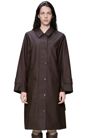 A woman wearing dark brown trench style jacket with shirt collar, set against a plain white background.