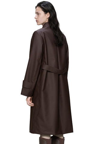 A woman shown from the back wearing a long dark brown trench coat with a matching waist belt, photographed against a plain white studio background.